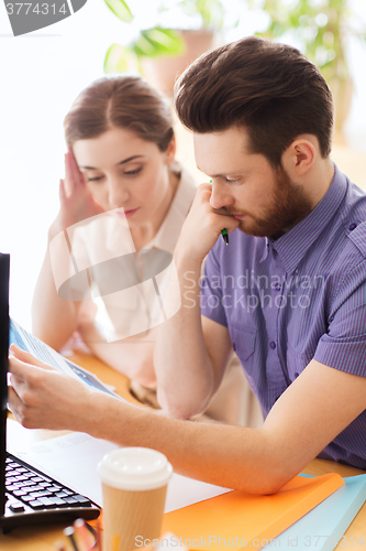 Image of creative team with reading paper in office