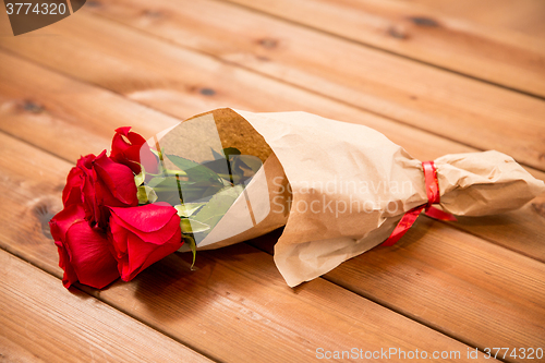 Image of close up of red roses bunch wrapped into paper