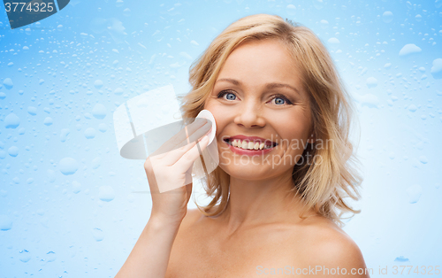 Image of happy woman cleaning face with cotton pad