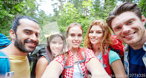 Image of friends with backpack taking selfie in wood