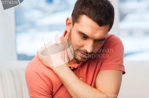 Image of unhappy man suffering from neck pain at home