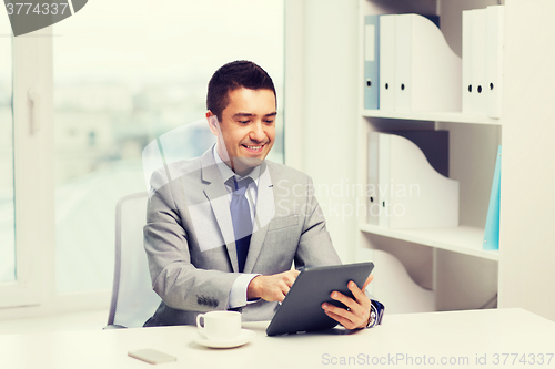 Image of smiling businessman with tablet pc and coffee cup