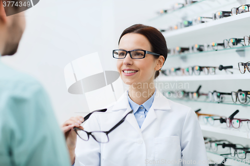 Image of optician showing glasses to man at optics store