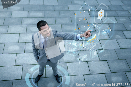 Image of smiling businessman with virtual screens outdoors