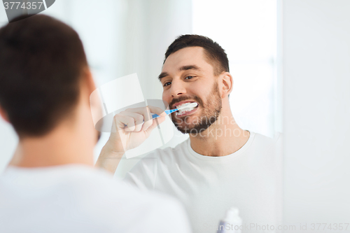 Image of man with toothbrush cleaning teeth at bathroom