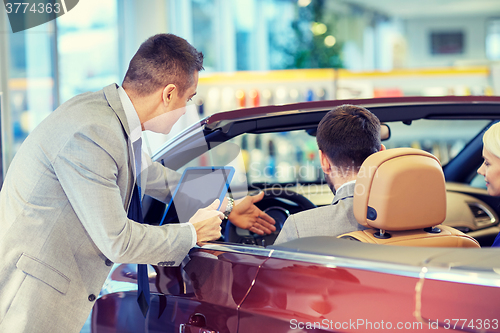 Image of happy couple with car dealer in auto show or salon