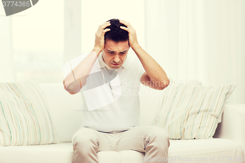 Image of unhappy man suffering from head ache at home