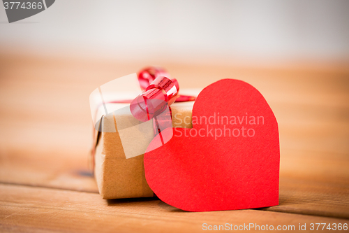 Image of close up of gift box and heart shaped note on wood