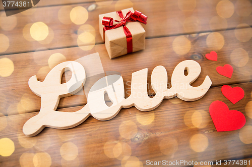 Image of close up of word love with gift box and red hearts