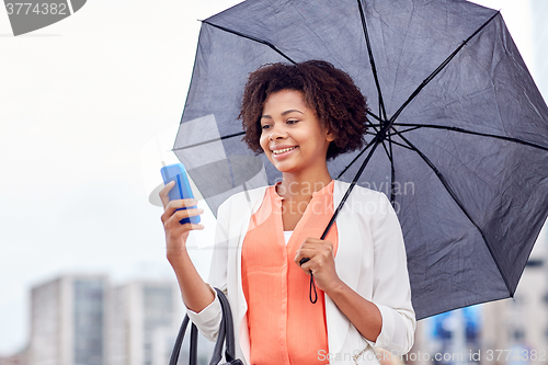 Image of businesswoman with umbrella texting on smartphone