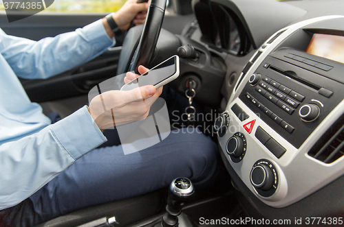 Image of close up of man with smartphone driving car