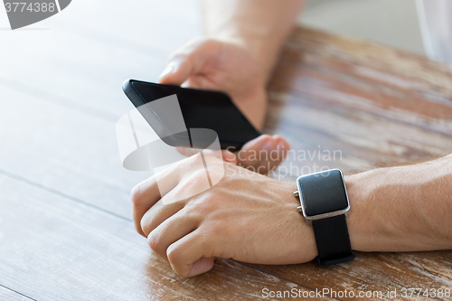 Image of close up of hands with smart phone and watch