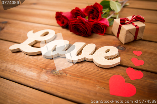 Image of close up of gift, word love, red roses and hearts