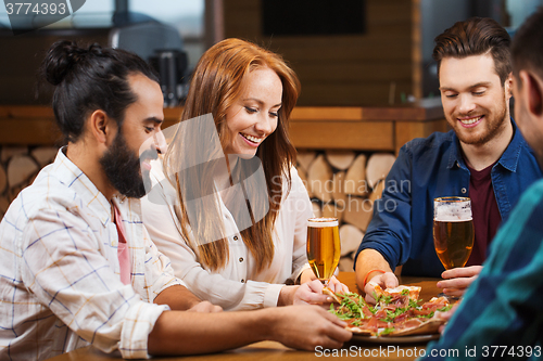 Image of friends sharing pizza with beer at pizzeria