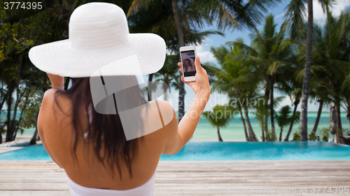 Image of woman taking selfie with smartphone on beach