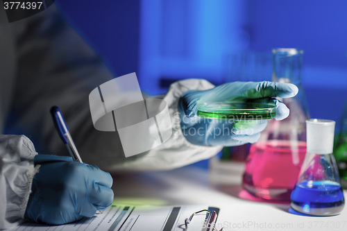 Image of close up of scientist writing test results in lab