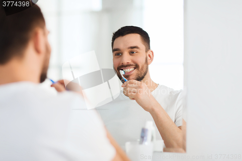 Image of man with toothbrush cleaning teeth at bathroom