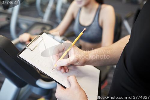 Image of close up of trainer hands with clipboard in gym