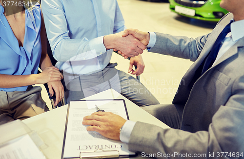 Image of handshake of customer and car dealer in auto salon