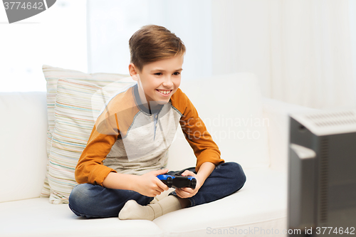 Image of happy boy with joystick playing video game at home