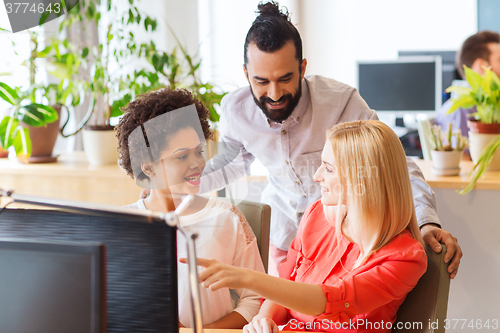 Image of happy creative team with computer in office