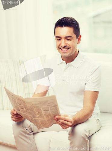 Image of happy man reading newspaper at home