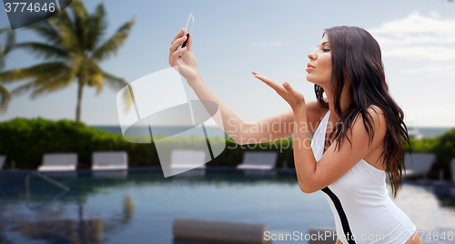 Image of young woman taking selfie with smartphone