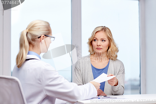 Image of doctor giving prescription to woman at hospital