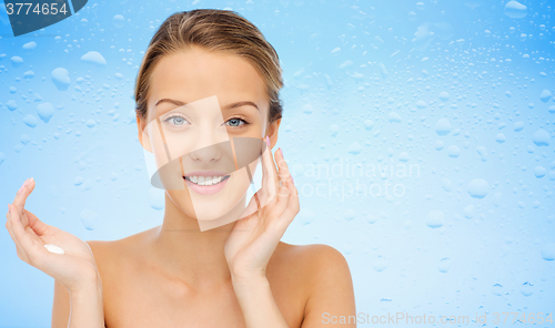 Image of happy young woman applying cream to her face