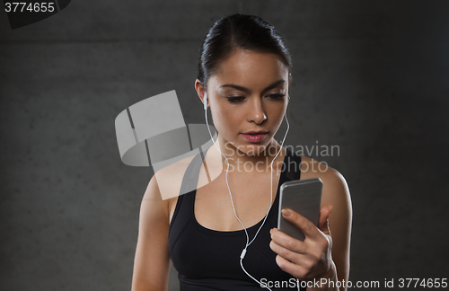 Image of woman with smartphone and earphones in gym