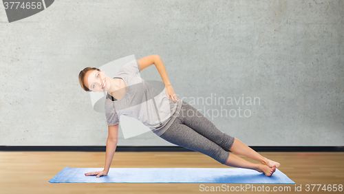 Image of woman making yoga in side plank pose on mat