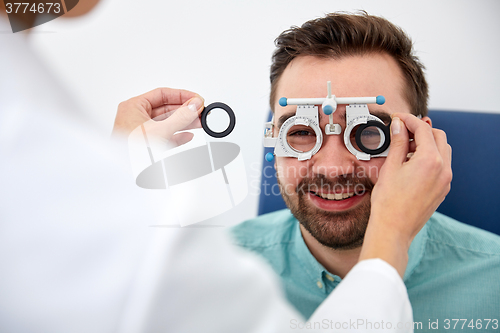 Image of optician with trial frame and patient at clinic