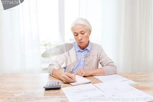 Image of senior woman with papers and calculator at home