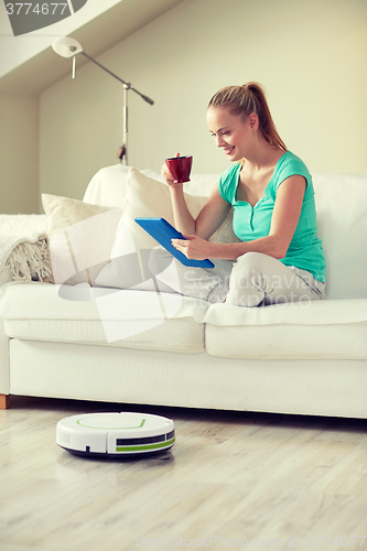 Image of happy woman with tablet pc drinking tea at home