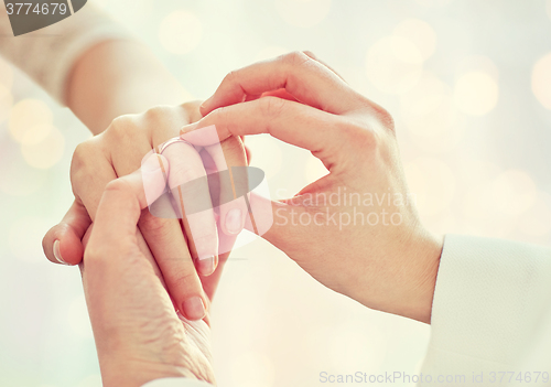 Image of close up of lesbian couple hands with wedding ring