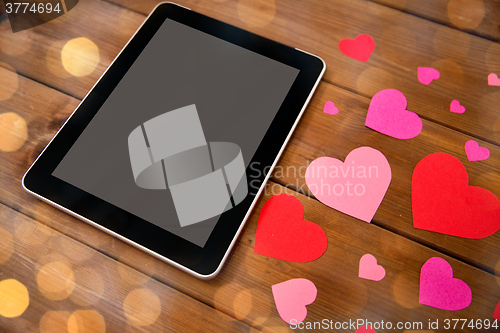 Image of close up of tablet pc and hearts on wood