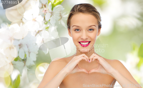 Image of smiling young woman showing heart shape hand sign