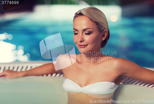 Image of happy womani sitting in jacuzzi at poolside