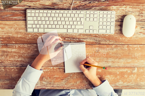 Image of close up of hands with notebook and keyboard