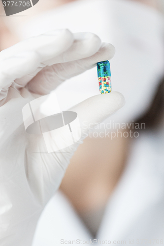 Image of close up of scientist holding pill in lab