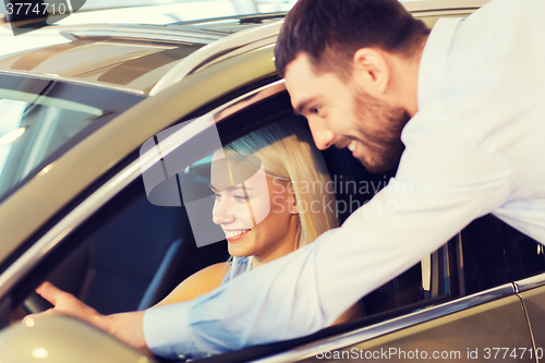 Image of happy couple buying car in auto show or salon