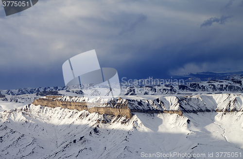 Image of Winter mountains at sun evening and gray storm clouds