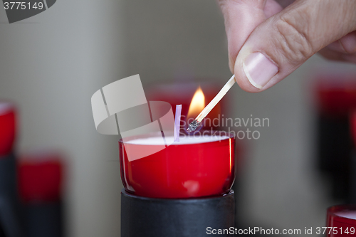 Image of Female mature woman burning candle light in church