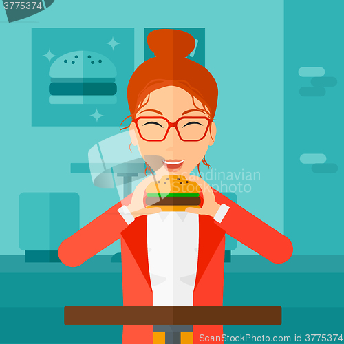 Image of Woman eating hamburger. 