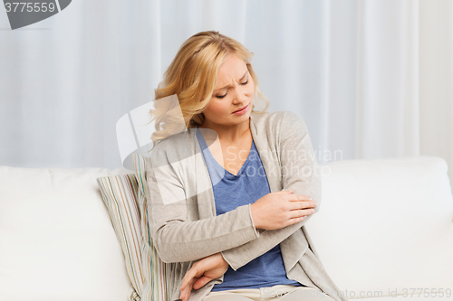 Image of unhappy woman suffering from pain in hand at home