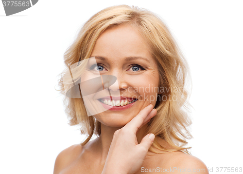 Image of smiling woman with bare shoulders touching face