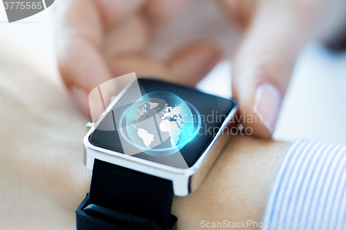 Image of close up of hand with globe hologram on smartwatch