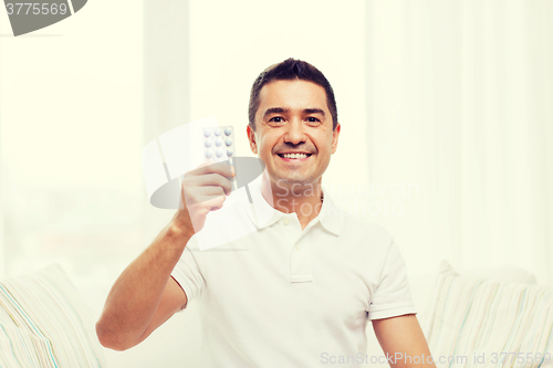 Image of happy man showing pack of pills at home