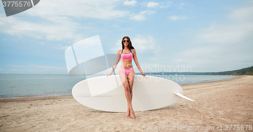 Image of smiling young woman with surfboard on beach