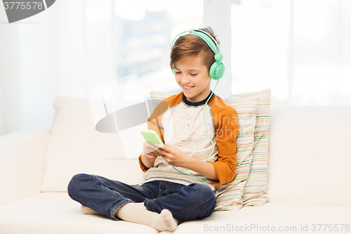 Image of happy boy with smartphone and headphones at home